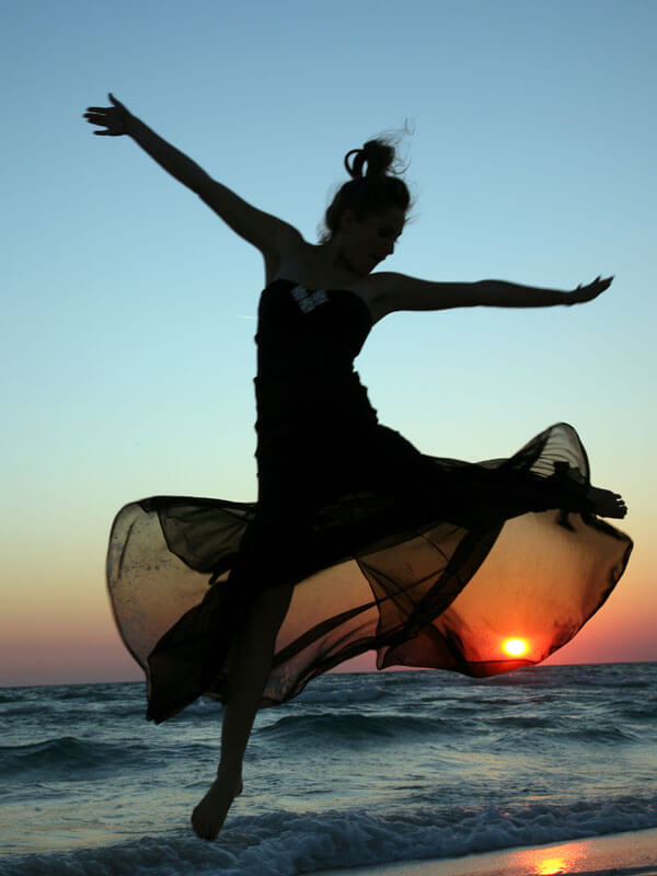 woman dancing on the beach at sunrise